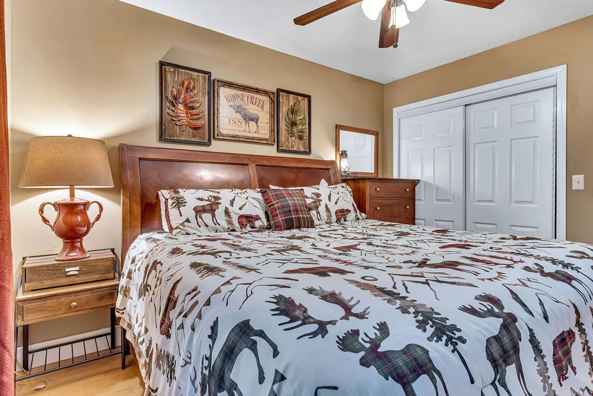 A warm, inviting bedroom featuring a bed with patterned bedding, a wooden nightstand, and decorative wall art—all thoughtfully arranged for comfort and style.