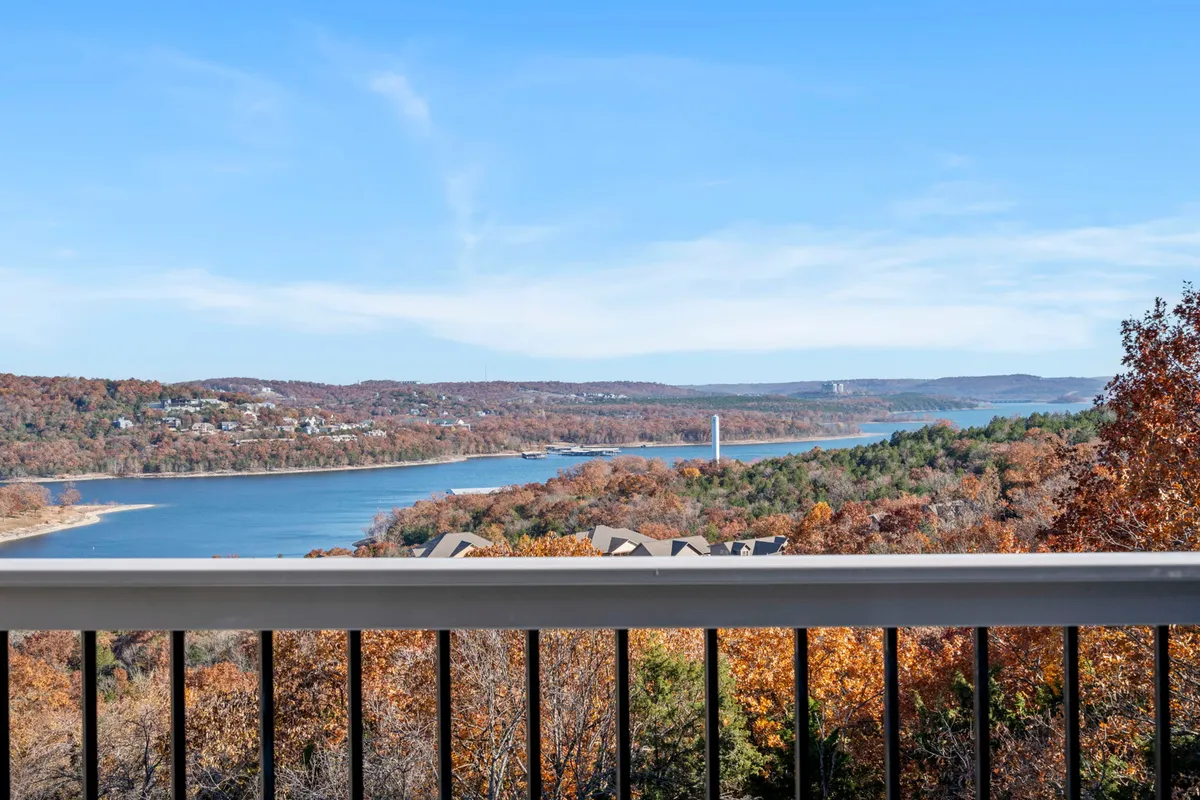 A breathtaking view of the lake framed by autumn foliage and rolling hills in the distance. The vantage point suggests a peaceful balcony or outdoor space perfect for soaking in natural beauty.