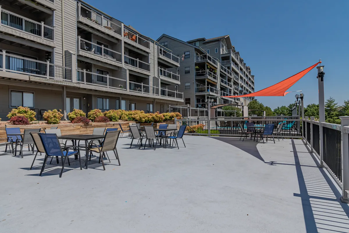 An inviting outdoor seating area furnished with comfortable chairs, vibrant planters, and a stylish shade structure. The space is designed for socializing, enjoying meals outdoors, or relaxing while soaking in the atmosphere.