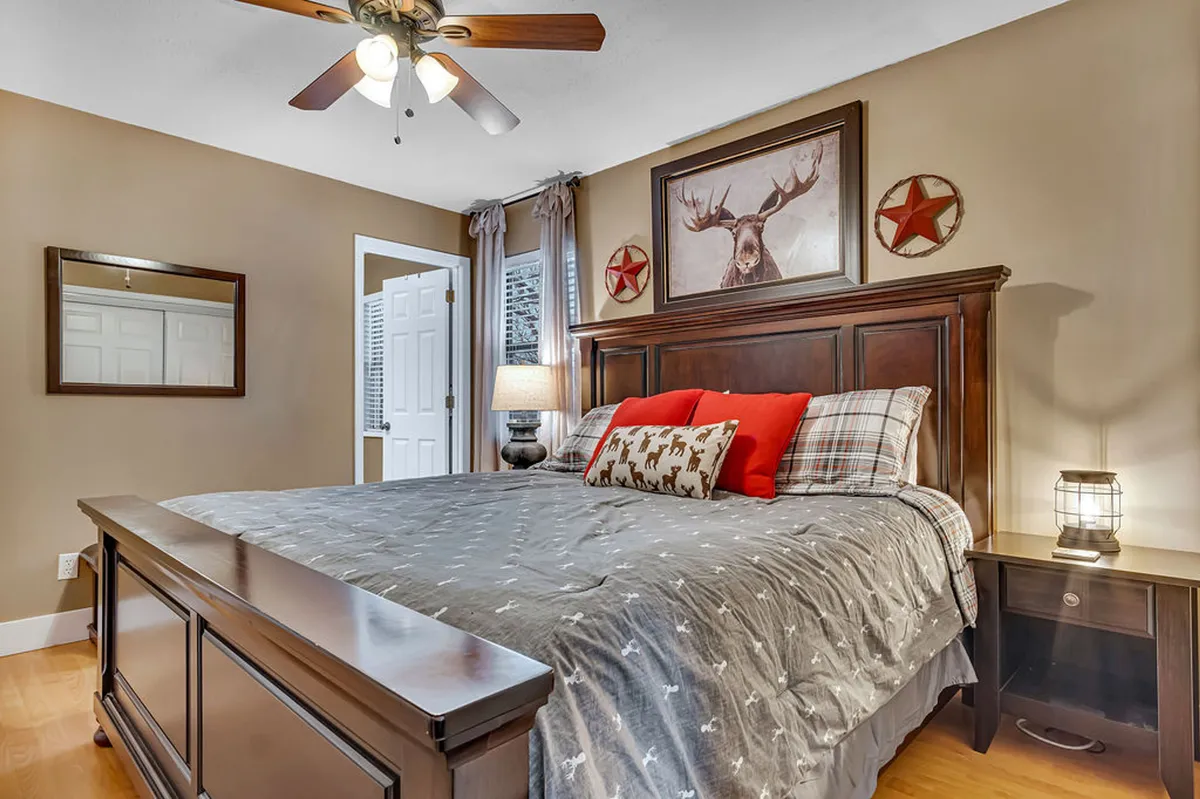 A cozy bedroom with a comfortable bed, soft lighting from a bedside lamp, stylish wall decor, and a mirror, creating an inviting and restful atmosphere.