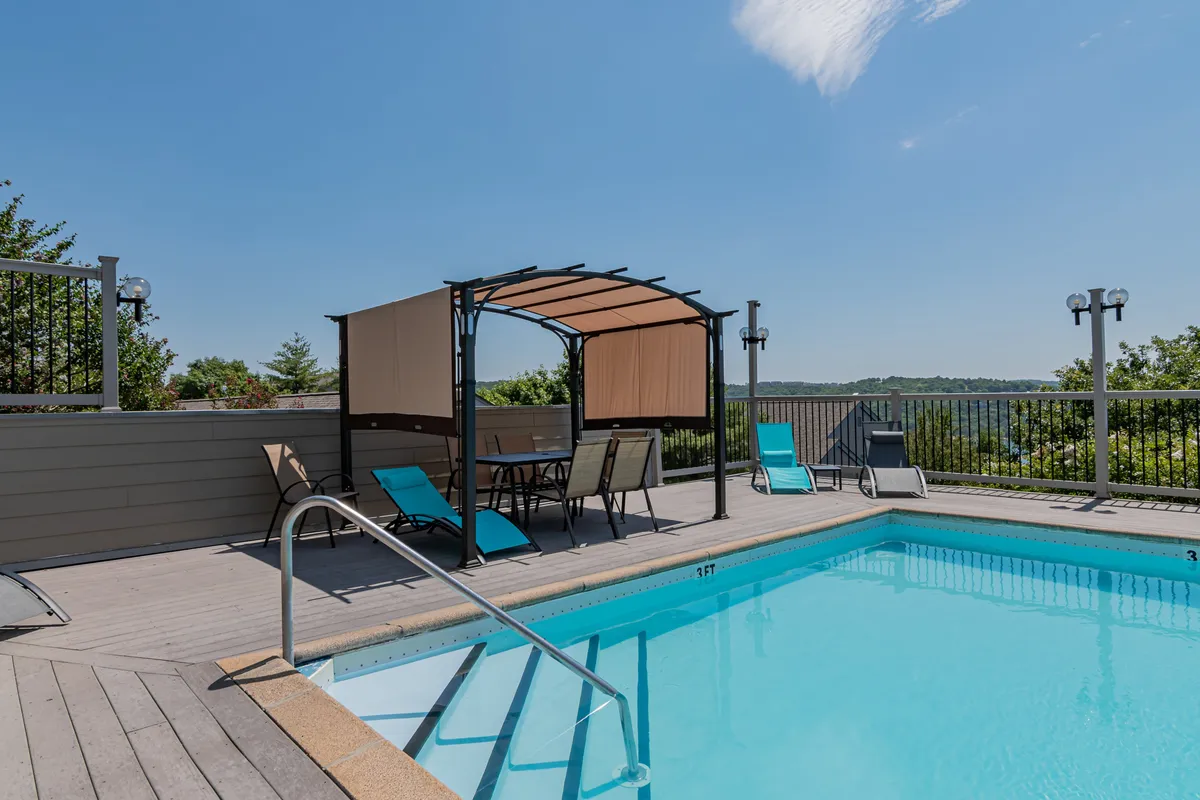 A sparkling outdoor swimming pool with a covered seating area nearby, set against a backdrop of landscaped greenery. The pool area looks inviting and tranquil, perfect for relaxation after a day of lake adventures.